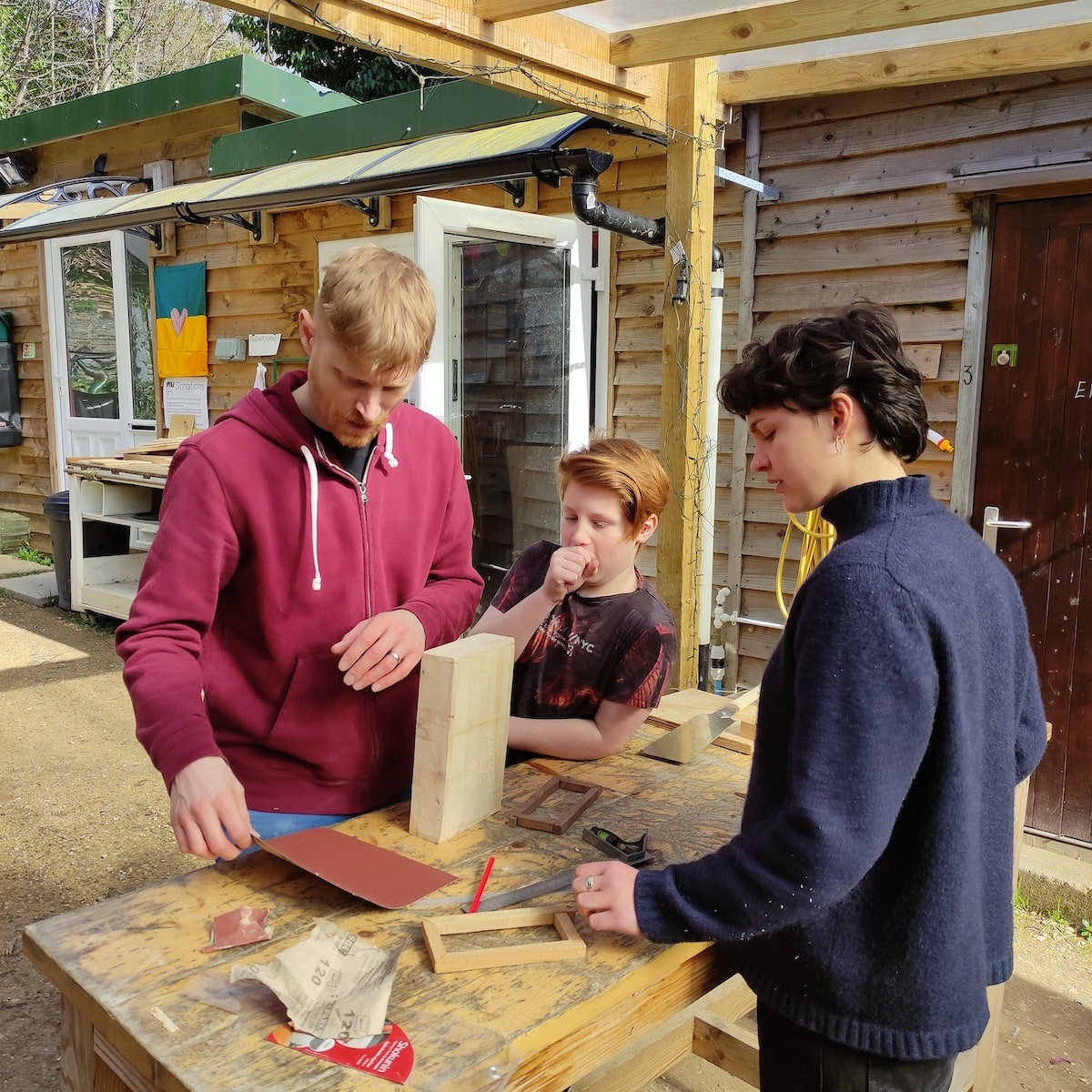 Georgina teaching a father and son simple joinery skills.