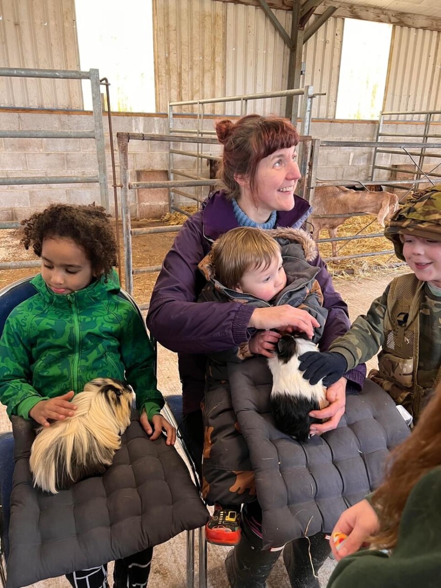 Parent and young children handling small animals at farm