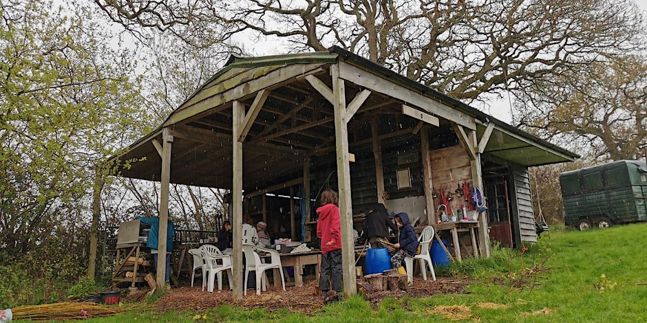 children under a wooden shelter at forest school