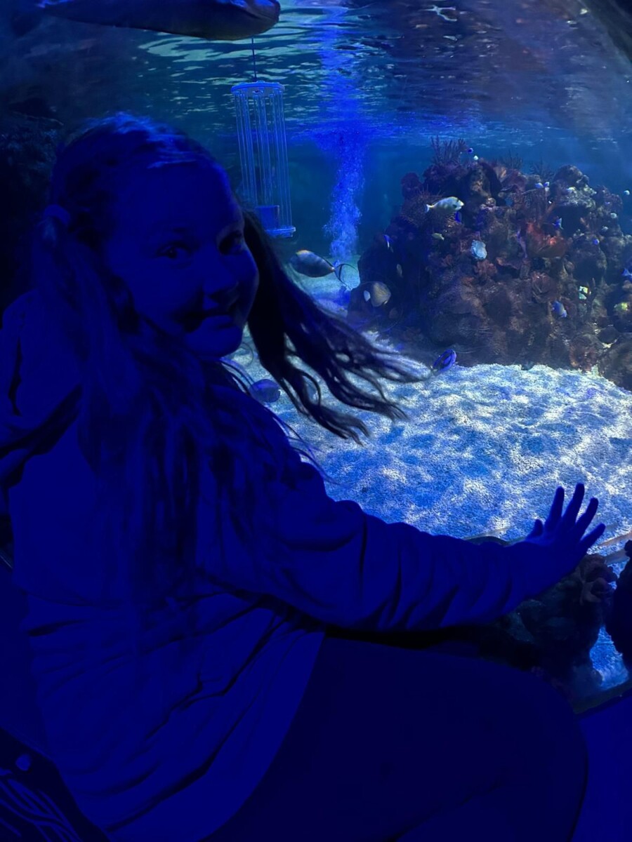 Smiling girl in the UV light of a shark tank in the dark